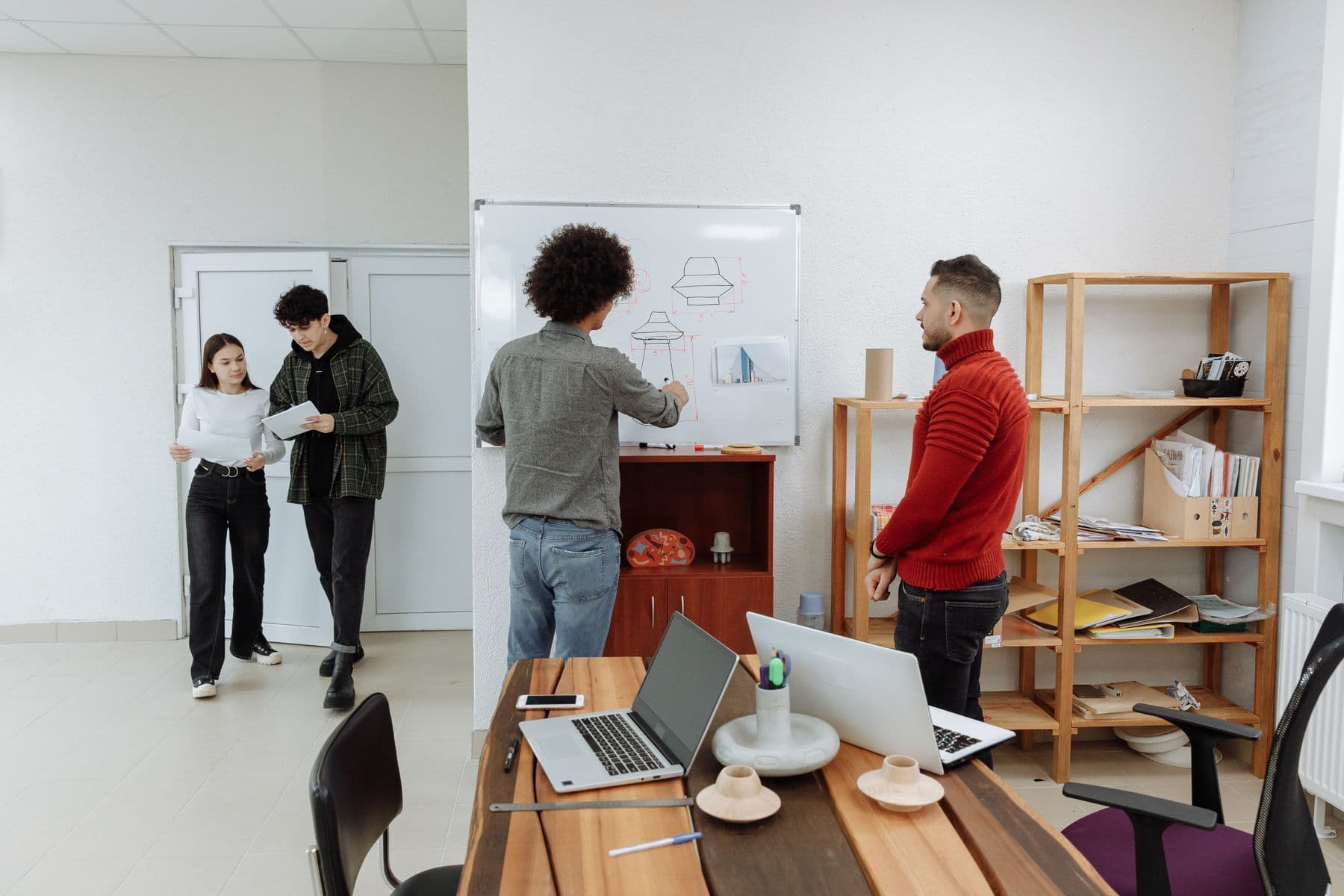 A small startup team talking through a product sketch at the office whiteboard